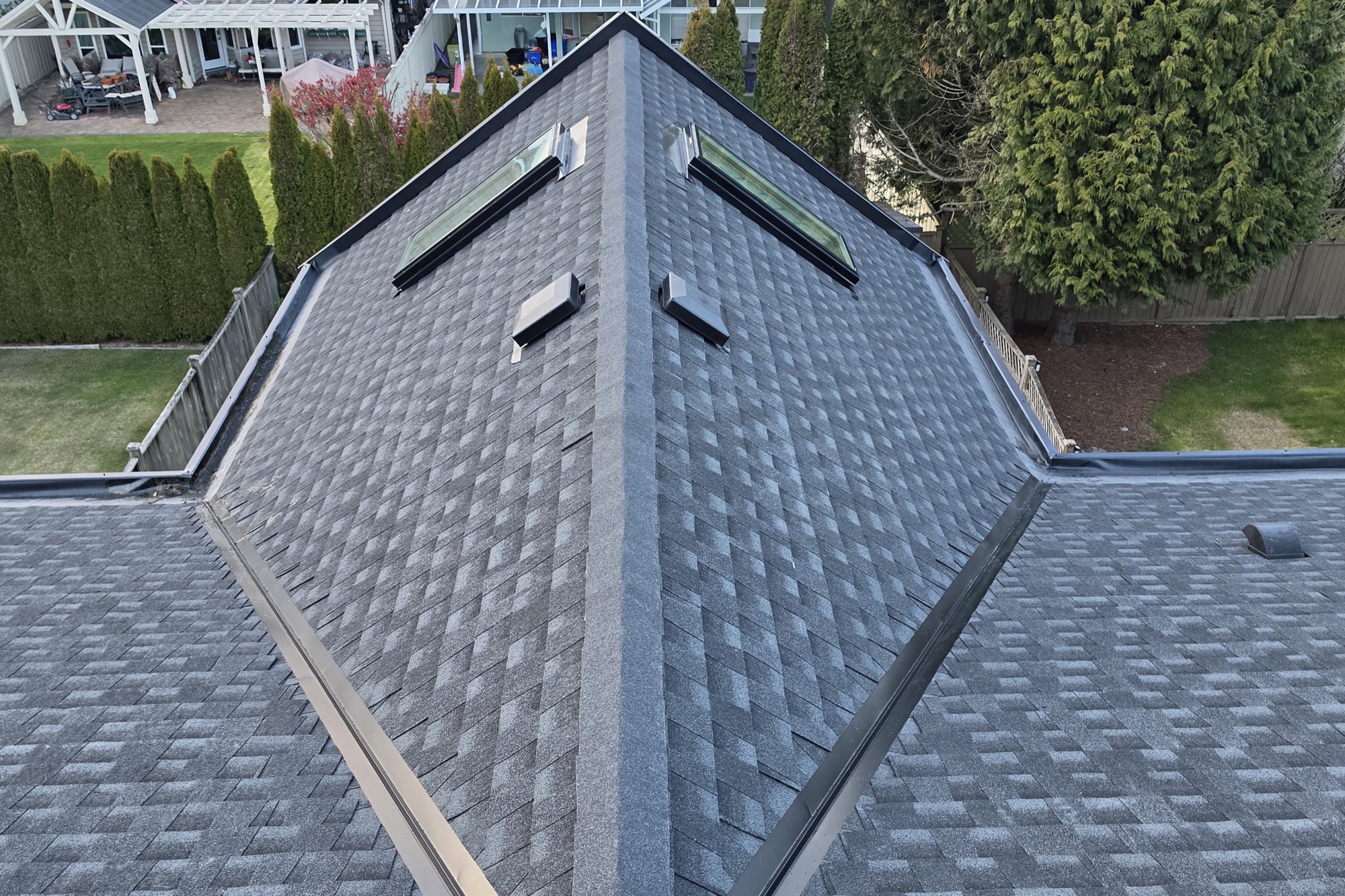 A finished asphalt shingle roof with two skylights, seen from above
