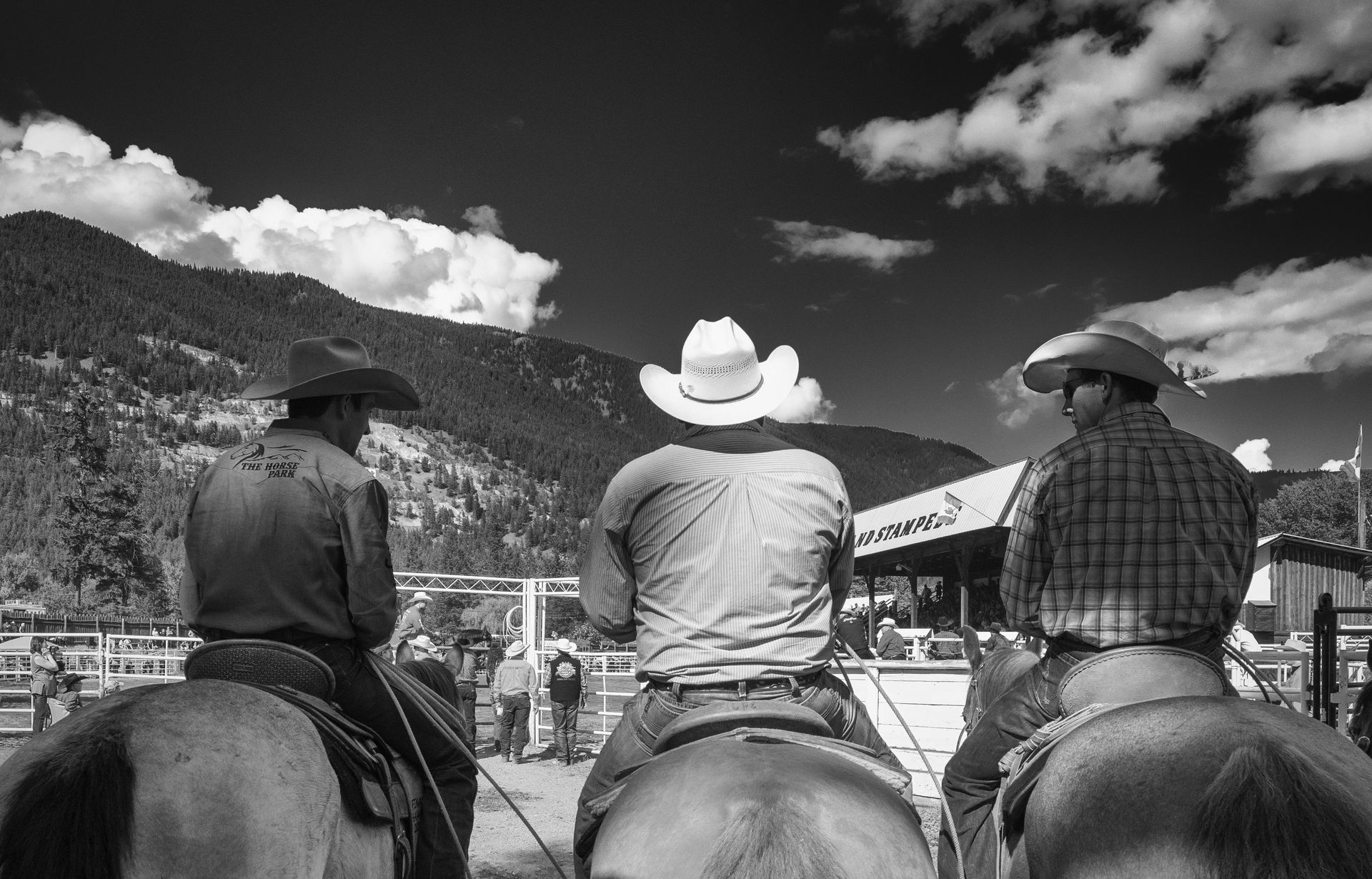 Three riders on horseback watching the arena at the Falkland Stampede